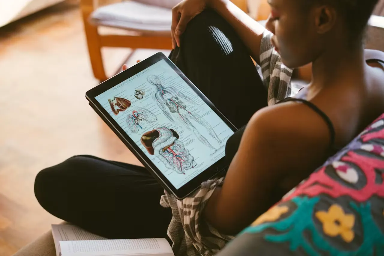 Woman studying anatomy diagrams at home on her tablet